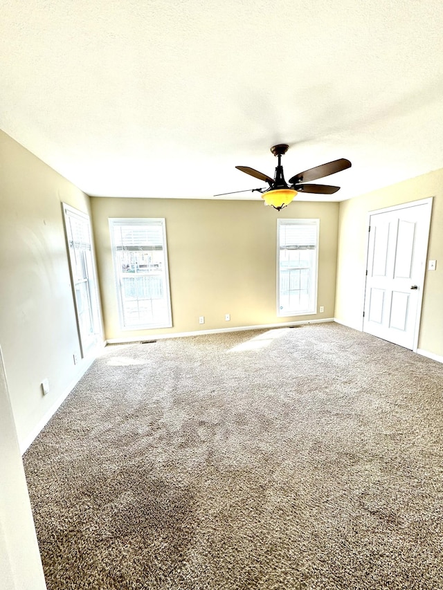 carpeted empty room with ceiling fan and a textured ceiling