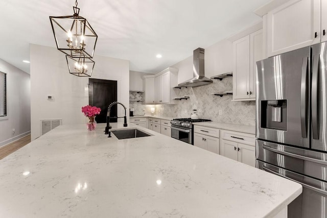 kitchen with appliances with stainless steel finishes, sink, hanging light fixtures, light stone countertops, and wall chimney exhaust hood