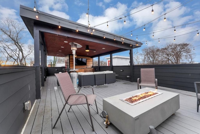 wooden deck with ceiling fan, a hot tub, and an outdoor living space with a fire pit