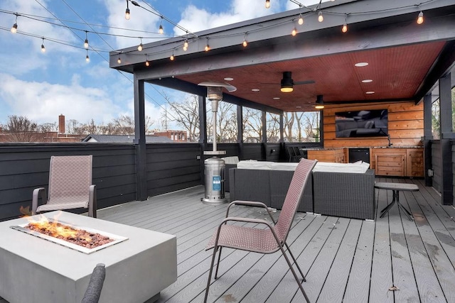 wooden deck with sink, an outdoor living space with a fire pit, and ceiling fan