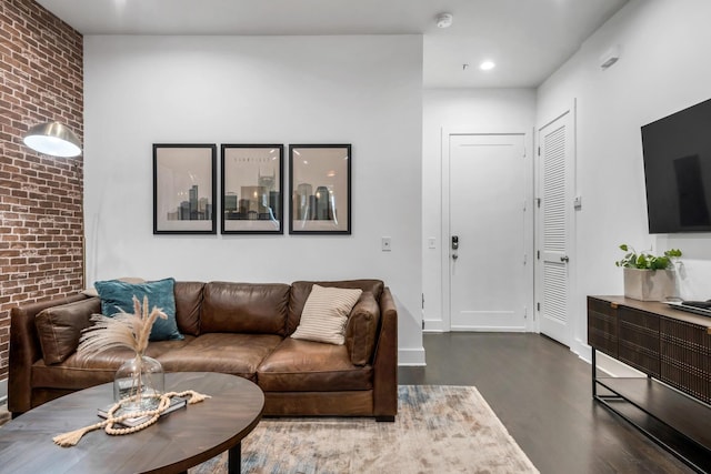 living room featuring hardwood / wood-style flooring and brick wall