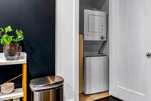 clothes washing area with stacked washer and dryer and hardwood / wood-style floors