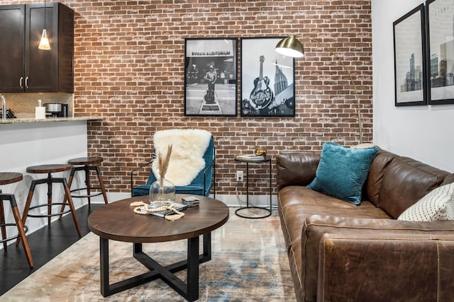 living room featuring brick wall and hardwood / wood-style floors