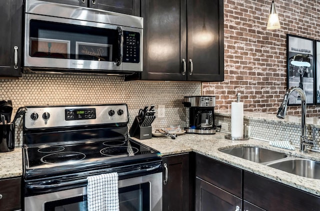 kitchen with dark brown cabinetry, sink, pendant lighting, stainless steel appliances, and backsplash