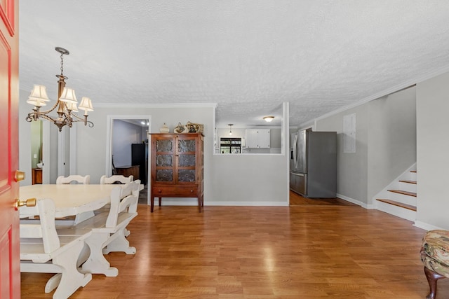 dining space featuring hardwood / wood-style flooring, crown molding, a chandelier, and a textured ceiling