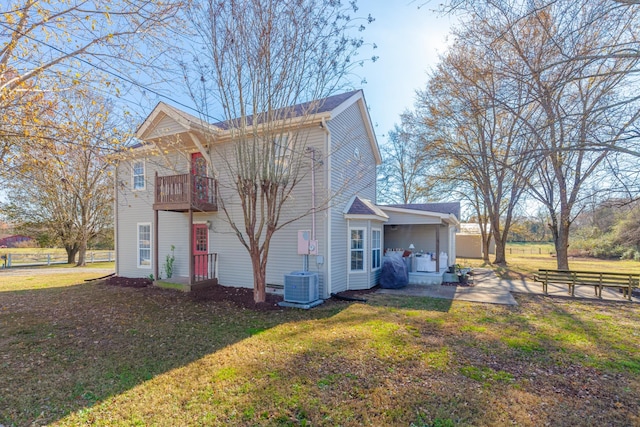 view of side of home featuring a yard, a patio area, a balcony, and central air condition unit