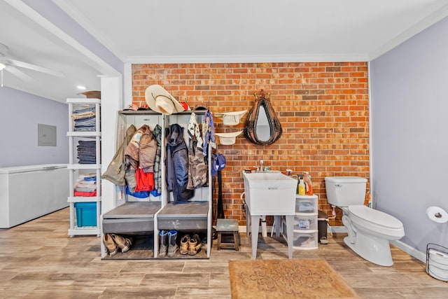 mudroom featuring hardwood / wood-style flooring, ceiling fan, brick wall, and crown molding