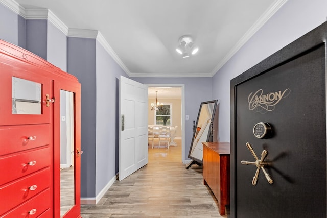 hallway featuring a notable chandelier, ornamental molding, and light hardwood / wood-style floors