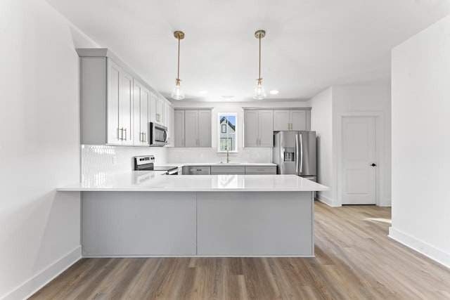 kitchen featuring a sink, stainless steel appliances, light countertops, and gray cabinetry