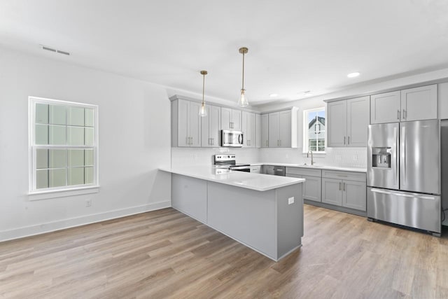 kitchen with tasteful backsplash, gray cabinets, visible vents, appliances with stainless steel finishes, and a peninsula