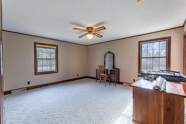 unfurnished office with crown molding, light colored carpet, ceiling fan, and a textured ceiling