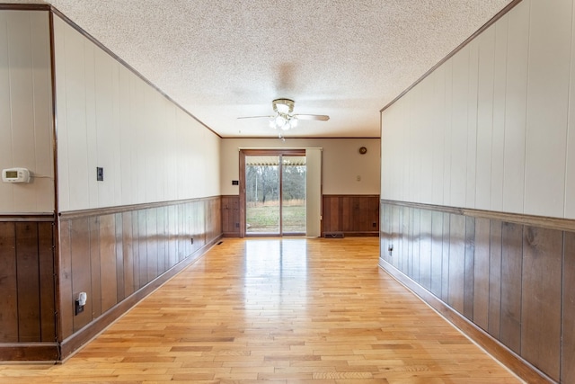 empty room featuring ceiling fan, ornamental molding, light hardwood / wood-style flooring, and a textured ceiling