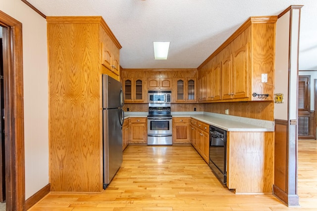 kitchen featuring stainless steel appliances, a textured ceiling, and light wood-type flooring