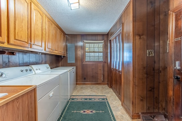 laundry room with cabinets, washing machine and dryer, electric panel, and wooden walls