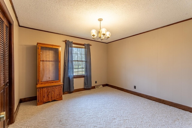 empty room featuring ornamental molding, a textured ceiling, light carpet, and a notable chandelier