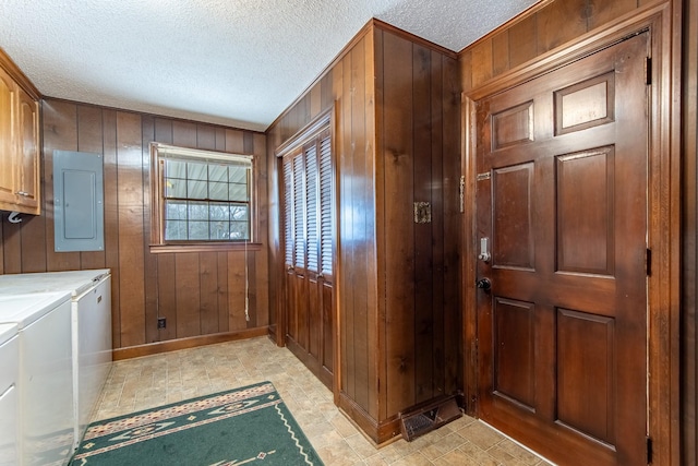 interior space with cabinets, wood walls, washing machine and clothes dryer, and electric panel