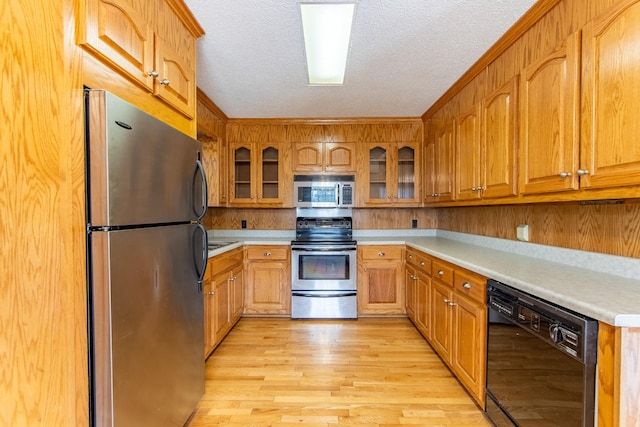 kitchen with appliances with stainless steel finishes, light hardwood / wood-style floors, and a textured ceiling