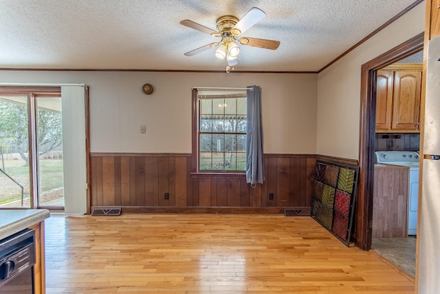 dining space with crown molding, washer / dryer, a textured ceiling, and light wood-type flooring