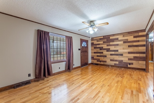 unfurnished room with ceiling fan, ornamental molding, light hardwood / wood-style flooring, and a textured ceiling