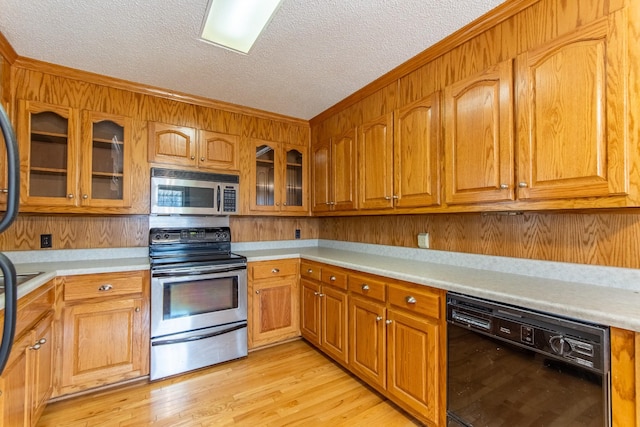 kitchen featuring crown molding, light wood-type flooring, a textured ceiling, and appliances with stainless steel finishes