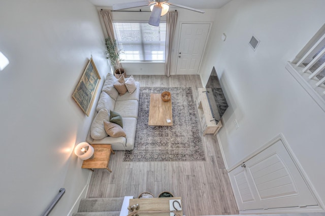 living room with light wood finished floors, ceiling fan, visible vents, and baseboards