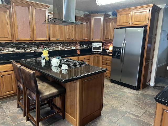 kitchen with a breakfast bar, black gas cooktop, stainless steel fridge, island exhaust hood, and decorative backsplash