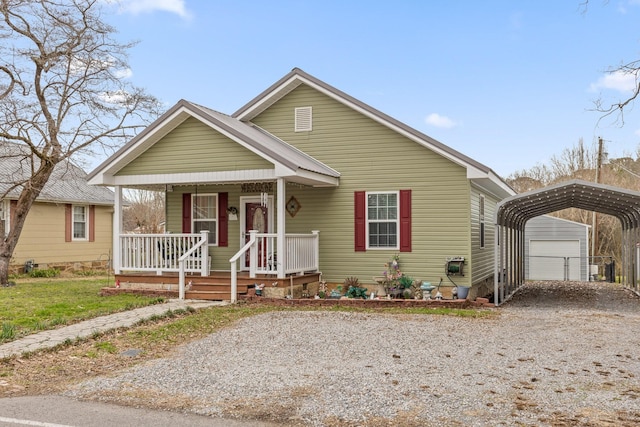 bungalow-style house with a carport, an outbuilding, covered porch, and driveway