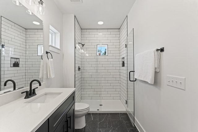 bathroom with vanity, a shower with door, and toilet