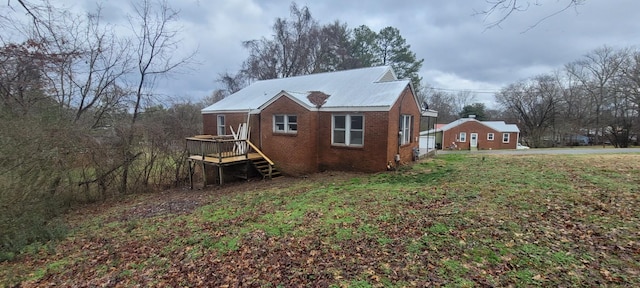 view of side of home with a deck and a lawn