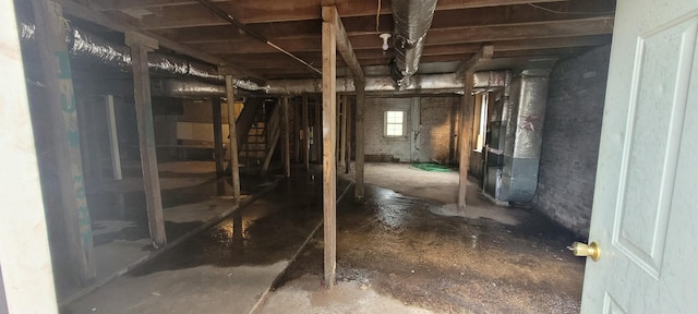 basement featuring brick wall and heating unit