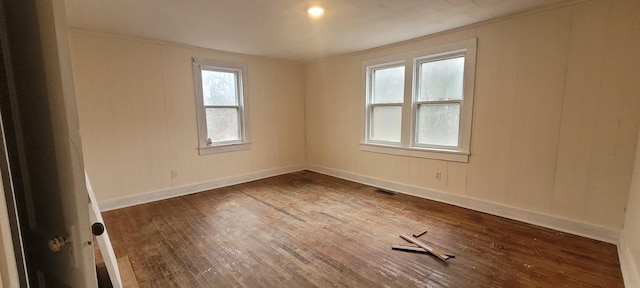 empty room featuring dark wood-type flooring and crown molding