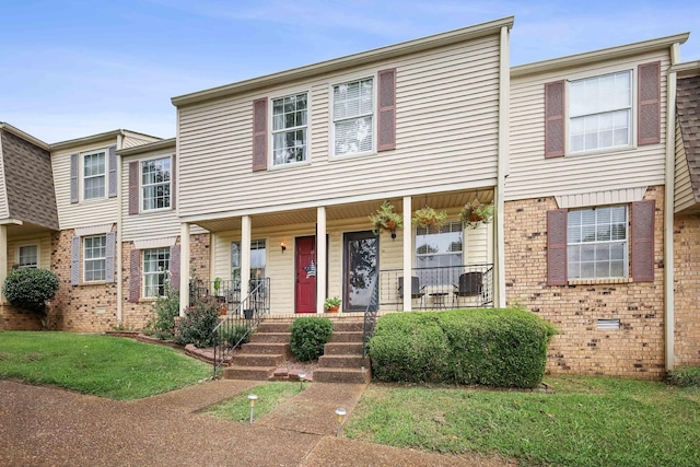 townhome / multi-family property with covered porch and a front yard