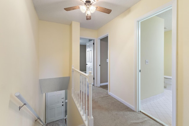 hall with light colored carpet and a textured ceiling