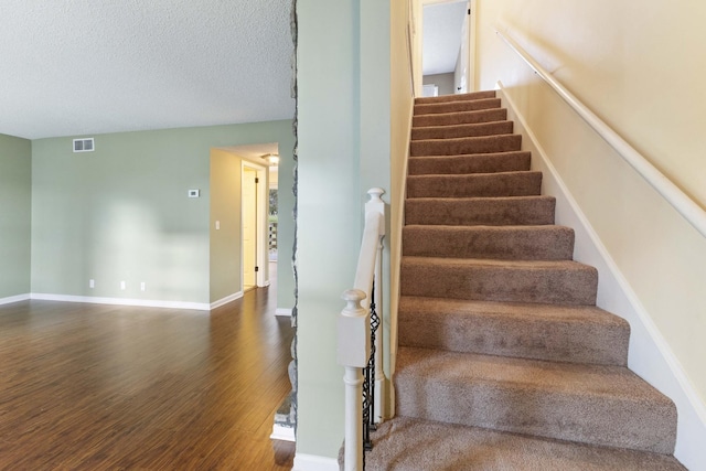 stairway featuring wood-type flooring and a textured ceiling