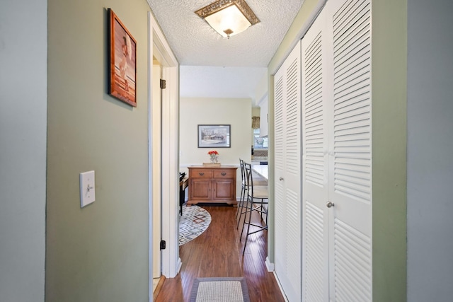 corridor with a textured ceiling and dark hardwood / wood-style flooring