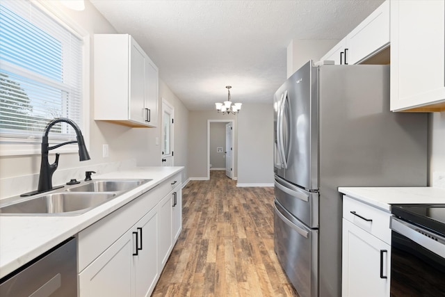 kitchen with sink, a chandelier, hanging light fixtures, appliances with stainless steel finishes, and white cabinets