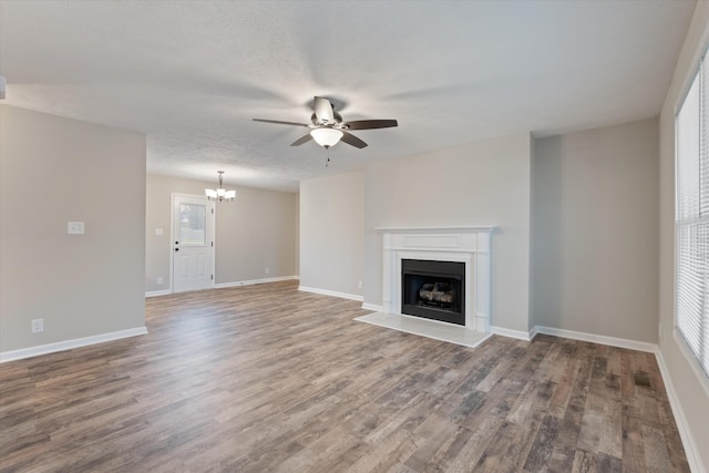 unfurnished living room featuring hardwood / wood-style floors, ceiling fan with notable chandelier, and a textured ceiling