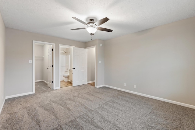 unfurnished bedroom featuring light colored carpet, a spacious closet, and a textured ceiling