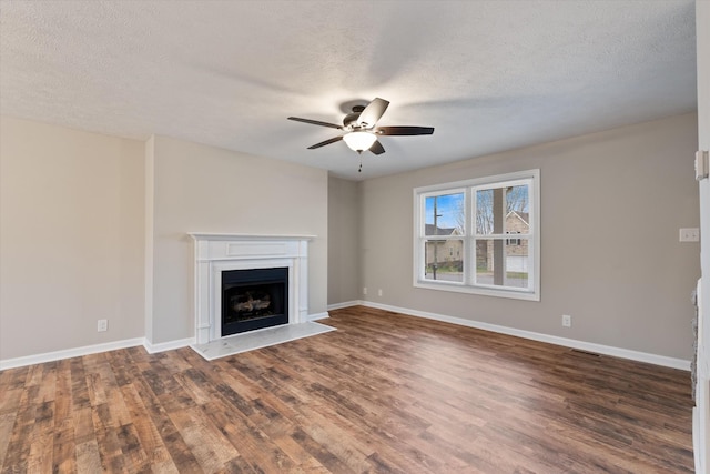 unfurnished living room featuring ceiling fan, dark hardwood / wood-style floors, and a textured ceiling