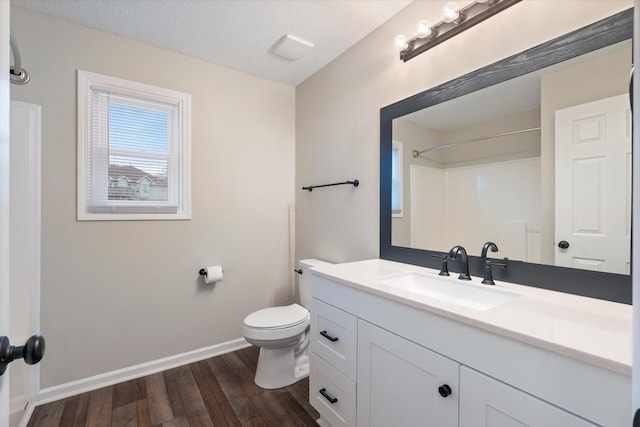 bathroom featuring hardwood / wood-style floors, vanity, a textured ceiling, a shower, and toilet