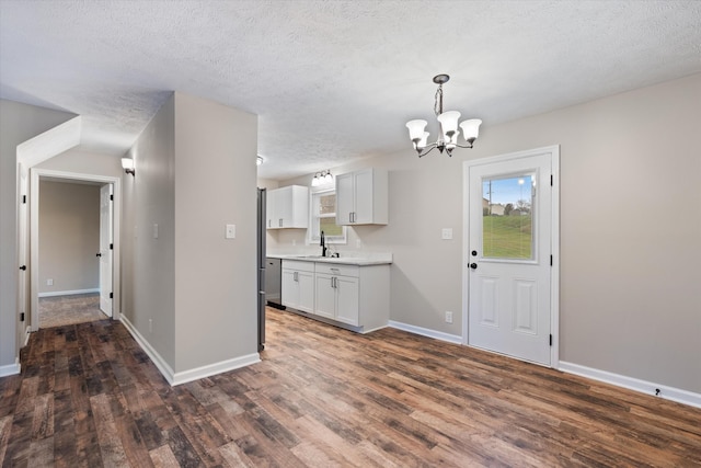 kitchen with sink, a textured ceiling, dark hardwood / wood-style flooring, pendant lighting, and white cabinets