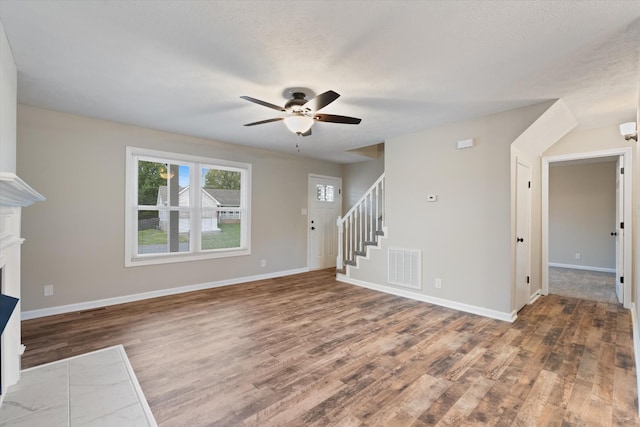 unfurnished living room with a textured ceiling, wood-type flooring, and ceiling fan