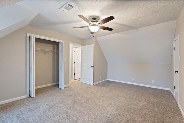 additional living space with vaulted ceiling, light carpet, ceiling fan, and a textured ceiling