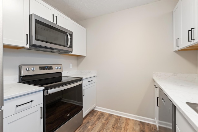 kitchen featuring light stone countertops, white cabinetry, appliances with stainless steel finishes, and dark wood-type flooring