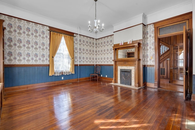 unfurnished living room featuring ornamental molding, a fireplace, dark hardwood / wood-style flooring, and a notable chandelier