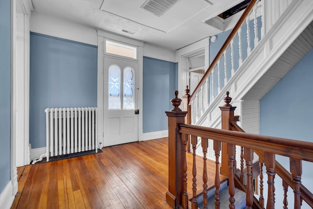 foyer entrance featuring hardwood / wood-style flooring, radiator heating unit, and a wealth of natural light