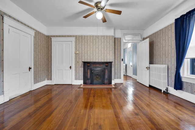 unfurnished living room with ceiling fan, dark hardwood / wood-style floors, and radiator