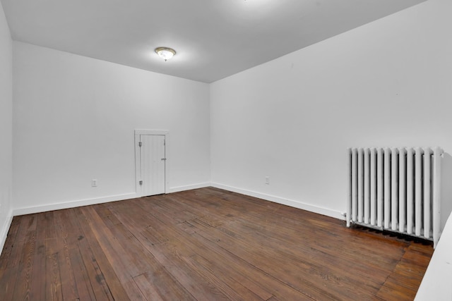 empty room with dark hardwood / wood-style flooring and radiator heating unit