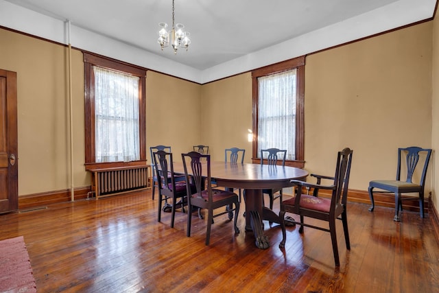 dining area featuring a chandelier, radiator, and dark wood-type flooring