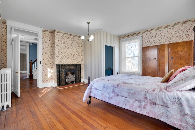 bedroom featuring hardwood / wood-style flooring, radiator, and a chandelier